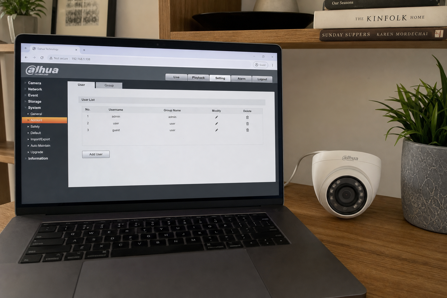 Home office desk with Dahua-style IP camera on shelf and laptop open to camera web settings user list